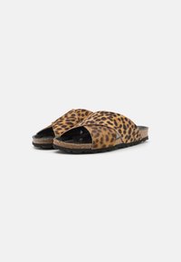 Brown leopard print slide sandals with crisscross straps, cork midsole, and black textured outsole. Features an open toe design.