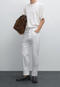 Jean en denim blanc, t-shirt en coton blanc à manches courtes, sac en daim marron et mocassins en cuir noir. Design simple et couleurs neutres.
