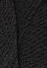 Tessuto nero testurizzato, con un aspetto morbido e intrecciato. Il materiale presenta un motivo in rilievo e una leggera lucentezza, con un design drappeggiato.