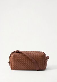 Ruda austyta odinė rankinė stačiakampio formos, užsegama užtrauktuku ir turi per petį nešiojamą dirželį. Turi lygų paviršių ir auksinius metalinius akcentus.