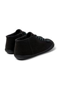 Scarpe alla caviglia nere in tela con finitura testurizzata, dotate di suole in gomma nera e lacci verde scuro. Dettagli con zip sul retro visibili.