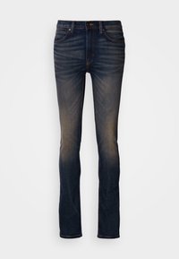 Jeans slim bleu foncé avec détails délavés sur les cuisses et les genoux, bouton et fermeture éclair à l'avant, et design à cinq poches.