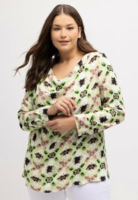 Långärmad blus i ett blommönster i grönt, rosa och svart. Har en draperad halsringning och ett mjukt, lättviktigt tyg.