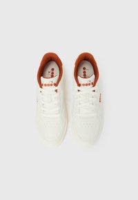 Par bijelih tenisica s unutarnjom oblogom i vezicama boje hrđe, pogled odozgo, na bijeloj pozadini s logotipom marke na uložcima i jezikom cipela.