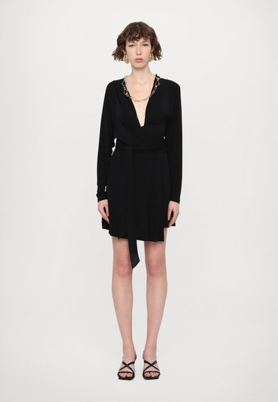 Svart omlottklänning med långa ärmar, djup V-ringning och knytband i midjan. Märkbar guldkedjedetalj runt halsringen. Mjuk tygstruktur.