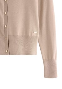 Cardigan beige lavorato a maglia con scollatura rotonda, chiusura a bottoni e polsini a costine. Presenta un piccolo logo metallico sulla parte inferiore.