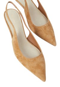Des talons slingback en suède beige avec un bout pointu, présentant des découpes sur les côtés et une semelle intérieure texturée, conçus pour un look ajusté.