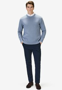 Ljusblå ribbad stickad tröja med rund halsringning, matchad med marinblå smal passform byxor och bruna mockaskor.