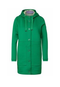 Cappotto verde con cappuccio realizzato in tessuto morbido, dotato di chiusura con cerniera e bottoni a pressione, due tasche frontali e coulisse decorative.