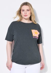 Camiseta gris oscuro de manga corta, que presenta un gráfico colorido del sol en el lado izquierdo del pecho. Material de algodón suave, ajuste relajado, cuello redondo.