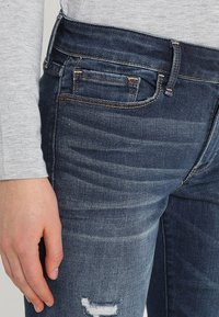 Bleka blå denimjeans med en nära passform, med ett slitet knä, fem fickor och tonad sömnad.