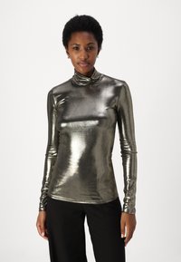 Ezüst metallic hosszúujjú garbó felső, testhez simuló kialakítással és sima textúrával. Fekete nadrággal párosítva.