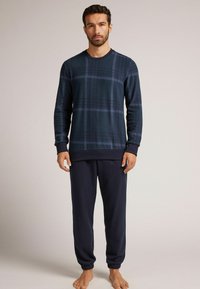 Heren loungewear set met een marineblauw geruit langSleeve T-shirt en bijpassende donkere broek, gemaakt van zachte stof met ribgebreide manchetten en een elastische tailleband.