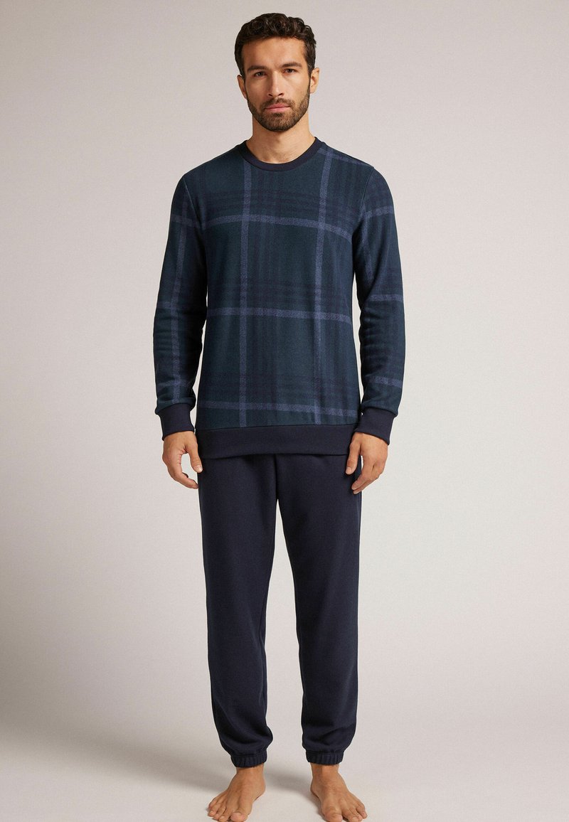 Heren loungewear set met een marineblauw geruit langSleeve T-shirt en bijpassende donkere broek, gemaakt van zachte stof met ribgebreide manchetten en een elastische tailleband.