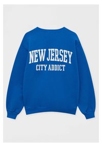 Sweat-shirt bleu col rond avec inscription blanche « NEW JERSEY » au-dessus de « CITY ADDICT » dans le dos, manches longues et bords-côtes aux poignets et à la taille.