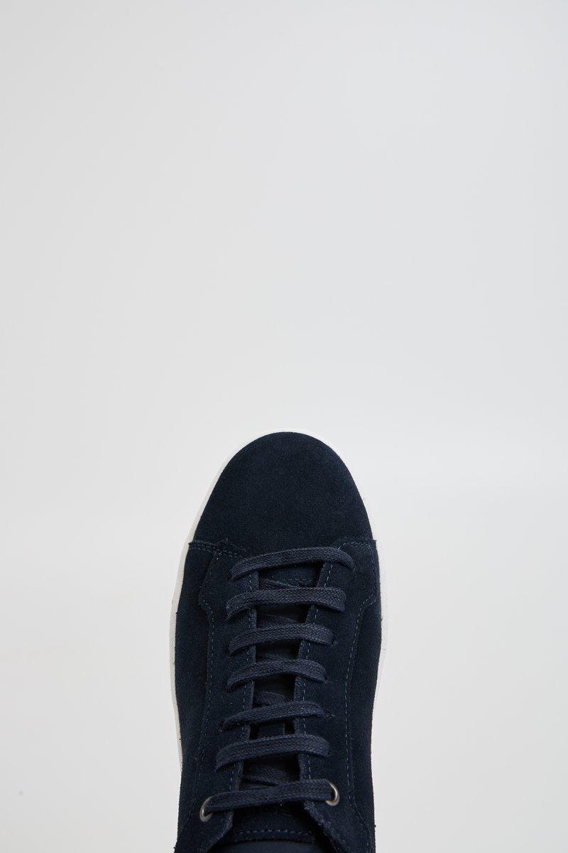 Sneaker in camoscio blu navy con punta arrotondata, lacci piatti e suola in gomma bianca. Presenta dettagli di cucitura lungo i lati.