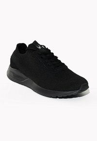 Scarpa sportiva nera con superiore in maglia testurizzata, punta arrotondata, chiusura con lacci e suola nera imbottita. Accentuata da un'etichetta con il logo.
