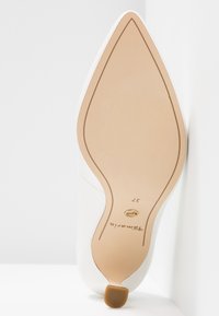 Semelle d'une chaussure blanche à bout pointu avec une base beige, petit talon, taille 37, portant la marque "Tamaris".