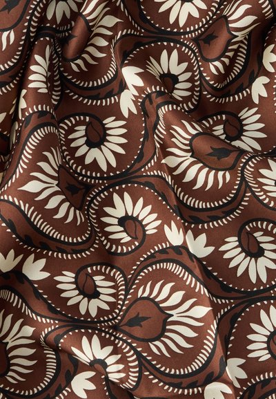 Tissu marron avec motifs floraux blancs et contours noirs, présentant des tourbillons et des courbes, créant un aspect texturé et superposé.