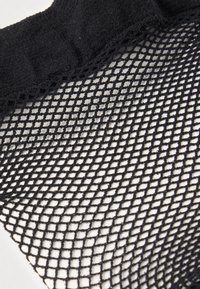 Tecido de rede preta com padrão aberto de diamantes e textura suave. A borda é acabada com uma faixa preta sólida e lisa.