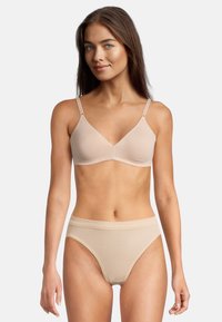 Reggiseno beige chiaro e slip abbinati, realizzati in tessuto liscio ed elastico. Il reggiseno presenta spalline sottili e un design a V. Semplice e senza cuciture.
