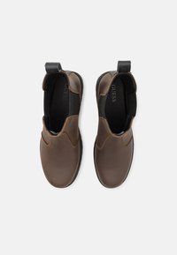 Brązowe skórzane botki typu chelsea z elastycznymi bokami, uchwytami do zakładania i gumowymi podeszwami. Gładka faktura z subtelnymi detalami przeszycia.