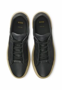 Black leather sneakers with a smooth texture, featuring a lace-up design, rubber sole, and subtle branding on the interior.