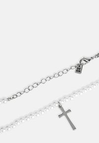 Pērļu kaklarota ar sudraba krusta piekari. Aprīkota ar ķēdes sprādzi un regulējamu garumu. Gluda tekstūra un spīdīga apdare.