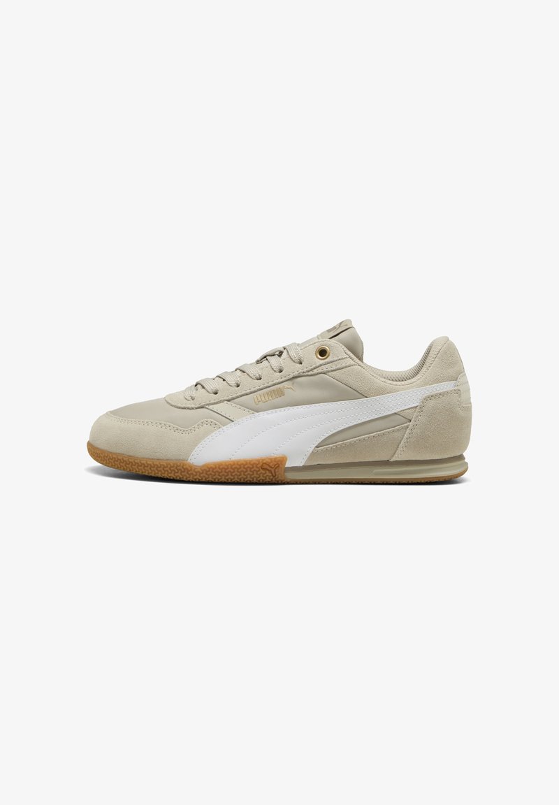 Beżowe sneakersy z białym paskiem po boku, wykonane z zamszu i skóry, związywane, z teksturowaną gumową podeszwą i złotymi oczkami.