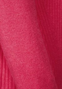 Roze gebreide stof met een fijne textuur, voorzien van ribbelpatronen. Het materiaal lijkt zacht en licht glanzend onder het licht.