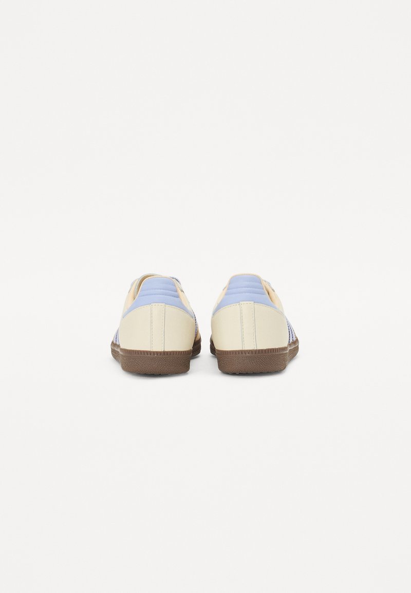 Sneakers met een lichtbeige leren bovenwerk, blauwe accenten en een gestructureerde rubberen zool. Voorzien van platte veters en stiksel details.