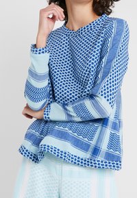 Maglione di cotone blu con vari motivi geometrici e texture. Maniche lunghe e vestibilità comoda con accenti blu a contrasto.