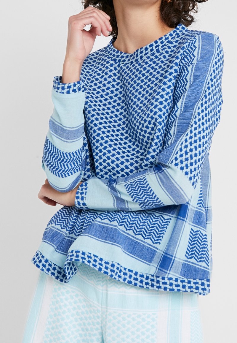 Maglione di cotone blu con vari motivi geometrici e texture. Maniche lunghe e vestibilità comoda con accenti blu a contrasto.