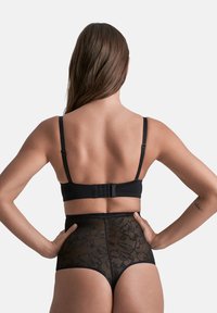 Zwarte bralette met verstelbare bandjes en haaksluiting, gecombineerd met hoge zwarte kanten slips met bloemenpatronen.