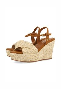 Sandalias de cuña con parte superior de fibra de yute trenzada, correas de cuero marrón y una base apilada texturizada con un acabado natural. Accesorios en tono dorado.