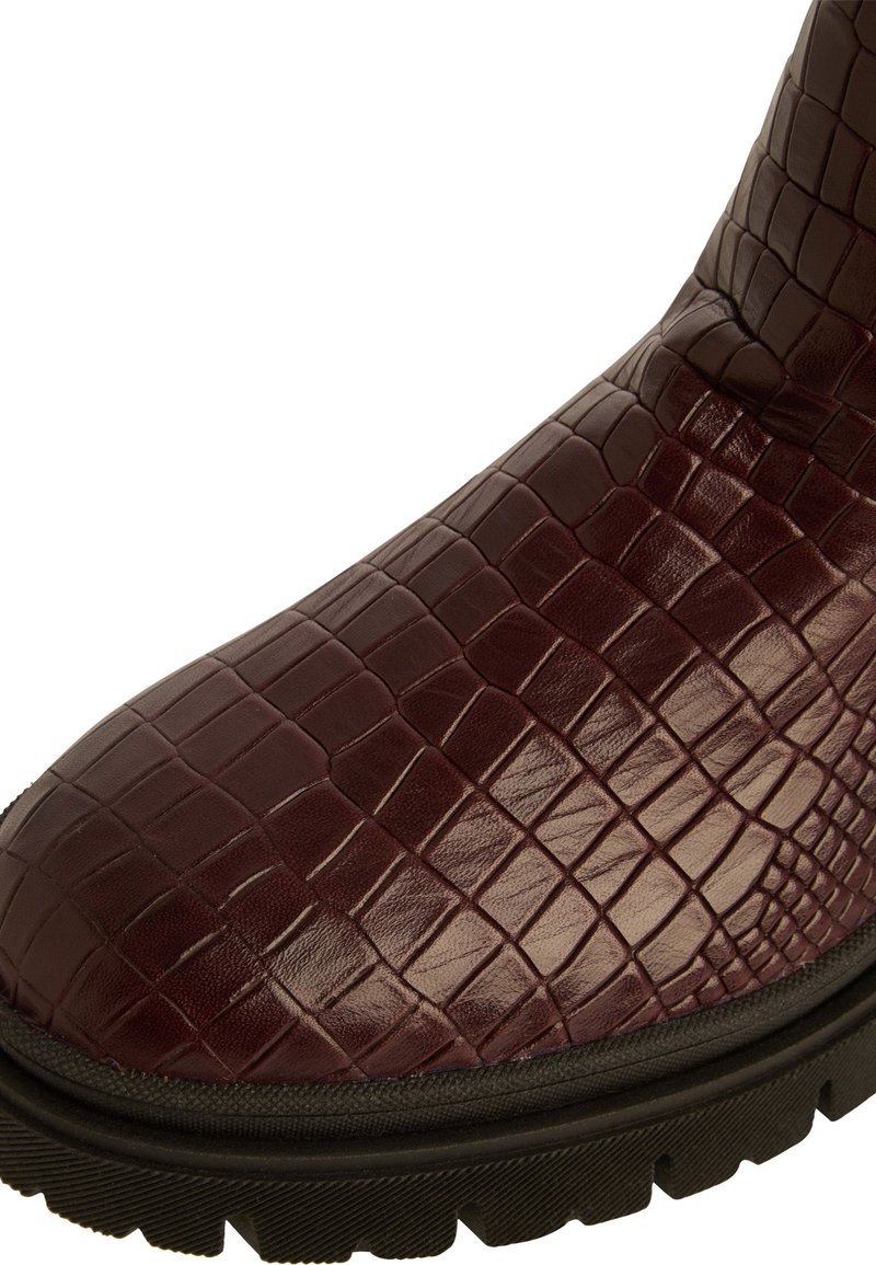 Bordeauxfarbene Leder-Stiefelette mit einem Krokodilmuster, ausgestattet mit einer schwarzen Gummisohle und einer strukturierten Oberfläch.
