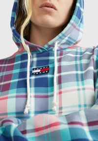 Niebiesko-różowy pikowany hoodie z bawełny. Posiada sznurek przy kapture i małą metkę z logo przy szyi. Miękka tekstura, casualowy design.
