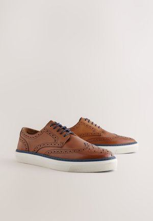 Brown leather shoes with wingtip design, perforations, and blue laces. White rubber sole with blue accents along the edge.