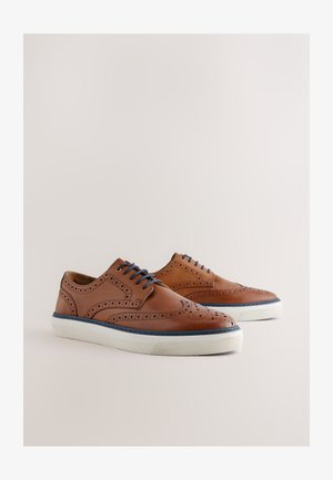 Ruskeat nahkakengät, joissa siipikuvio, rei'itykset ja siniset nauhat. Valkoinen kumipohja, jossa sinisiä yksityiskohtia reunoilla.