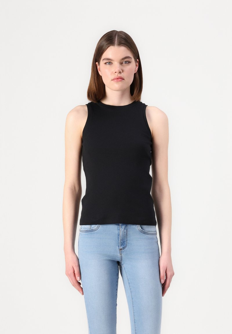 Black ribbed tank top with rounded neckline and sleeveless design. Paired with light blue skinny jeans, creating a fitted silhouette.