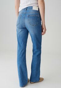 Lichtblauwe flared jeans van denim met een hoge taille, voorzien van achterzakken, subtiele vervaging en een eenvoudige witte leren label bij de tailleband.