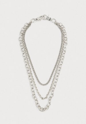 Három rétegű ezüst lánc nyaklánc, különböző méretű szemekkel, csillagkapoccsal, sima fehér háttéren.