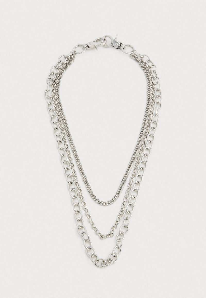 Τριών επιπέδων αλυσίδα από ασημί με διάφορους μεγέθους κρίκους και κούμπωμα τύπου αστακού σε απλή λευκή φόντο.