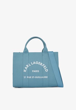 Sinine kangast kott, millel on kaks käepidet ja reguleeritav rihm. Ees on tekst: "KARL LAGERFELD PARIS 21 RUE ST-GUILLAUME." Tekst on valge.