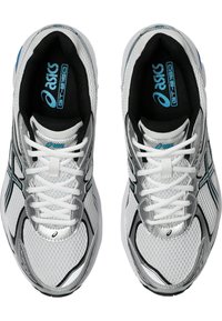 Białe buty sportowe z srebrnymi akcentami, siateczkowa cholewka, czarne wykończenie i niebieskie logo. Posiadają wyściełany język i sznurowadła na solidnej konstrukcji.