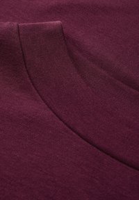 Tela de un burdeos profundo con una textura suave, que presenta un escote liso y una ligera curvatura a lo largo de los bordes. Diseño simple y sin costuras.