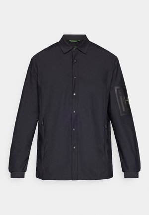 Crna jakna dugih rukava s kopčanjem na gumbe sprijeda, bočnim džepovima i džepom sa zatvaračem na lijevom rukavu. Glatka tekstura tkanine, minimalistički dizajn.