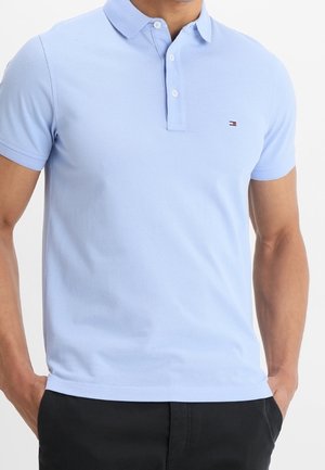 Hellblaues Polohemd aus Baumwolle mit einem Kragen mit drei Knöpfen, kurzen Ärmeln und einem kleinen Logo auf der linken Brust.