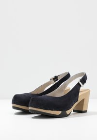 Svarta mocka slingback-klackar med rund tå, träblockklack och justerbart ankelskaft. Texturerad sula för bra grepp.