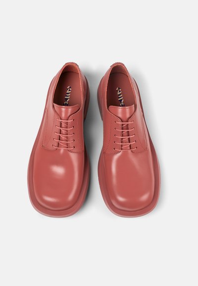 Red leather shoes with a smooth finish, rounded toe, and classic lace-up design. Features stitched detailing and a textured inner lining.